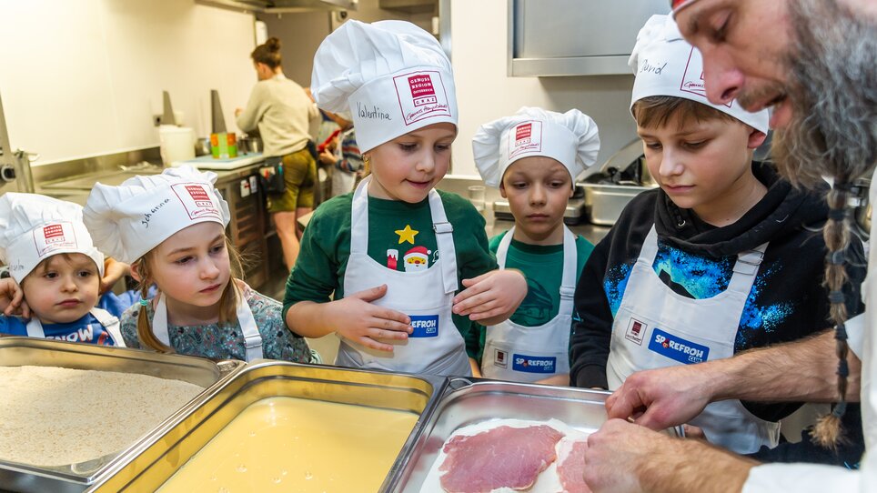 Kinder lernen beim Kochen, während ein Koch ihnen zeigt, wie man Wiener Schnitzel zubereitet. | © Graz Tourismus - Paul Stajan