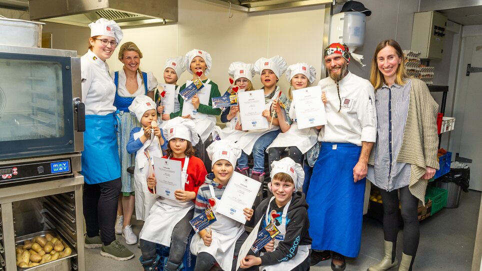 Gruppe von Kindern und Köchen nach einem Kochkurs in Graz mit Urkunden in den Händen. | © Graz Tourismus - Paul Stajan