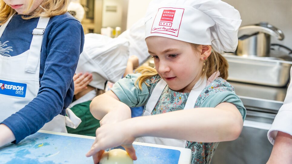 Mädchen bei einem Kochkurs, das Gemüse schneidet. | © Graz Tourismus - Paul Stajan