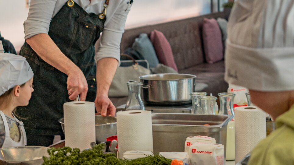 Ein Koch zeigt Kindern bei einem Kochkurs, wie man mit frischen Zutaten kocht. | © Milena Bonstingl