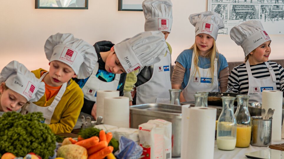 Kinder beim Kochen mit Chefkochmützen in Graz. | © Milena Bonstingl