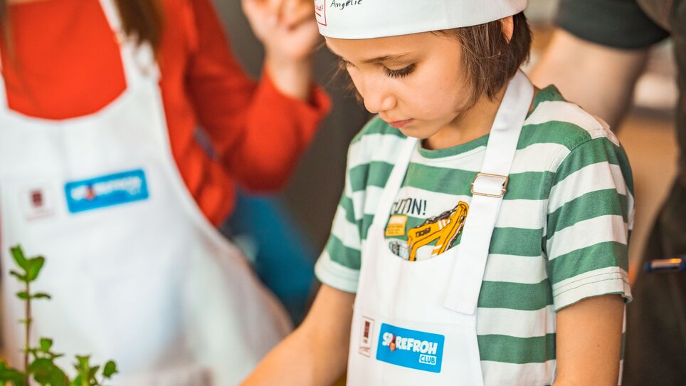 Kinder lernen Kochen in Graz mit Schürzen und Kochhauben. | © KHC - Bernhard Schindler