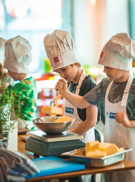 Kinder mit Kochmützen bei einem Kochkurs in Graz. | © KHC - Bernhard Schindler
