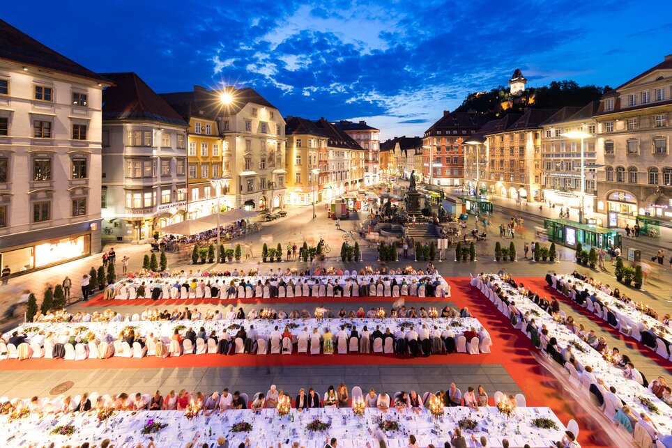 Lange Tafel der GenussHauptstadt in Graz I Steiermark | © Graz Tourismus - Harry Schiffer Eine lange Tafel, beleuchtet unter dem Abendhimmel, in Graz. | © Graz Tourismus - Harry Schiffer