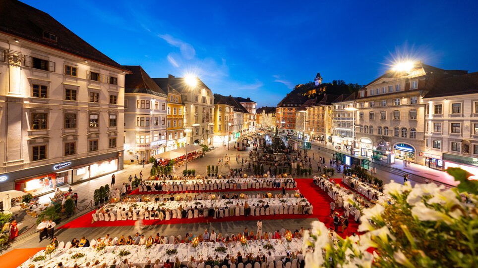 Lange Tafel der GenussHauptstadt am Grazer Hauptplatz bei Dämmerung - mit Blick auf den Grazer Uhrturm. | © Graz Tourismus - Harry Schiffer