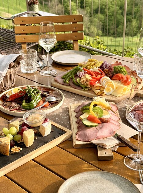 Tavolo con vari piatti, bicchieri di vino e vista bella. | © Schanzlwirt