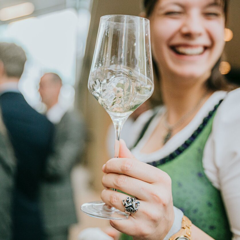 Präsentation des Steirischen Weins in der Grazer Stadthalle | © Wein Steiermark - Johanna Lamprecht Lächelnde Frau hält ein Weinglas, während sie in einer festlichen Umgebung ist. | © Wein Steiermark - Johanna Lamprecht