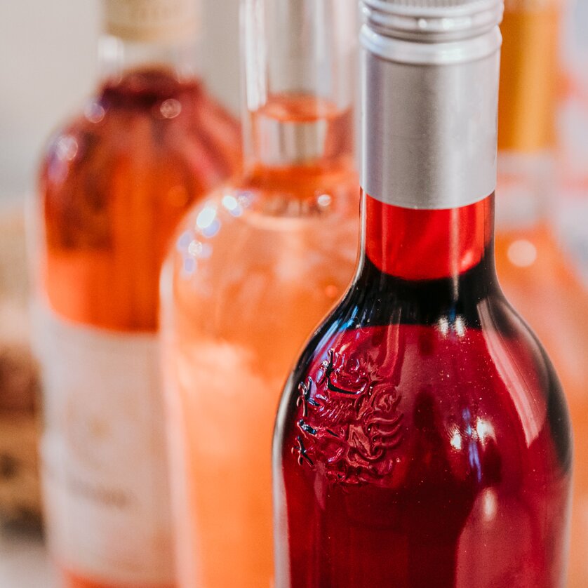 Close-up of three wine bottles with wine in different shades of rosé, from a delicate peachy pink to a strong light red. | © Johanna Lamprecht
