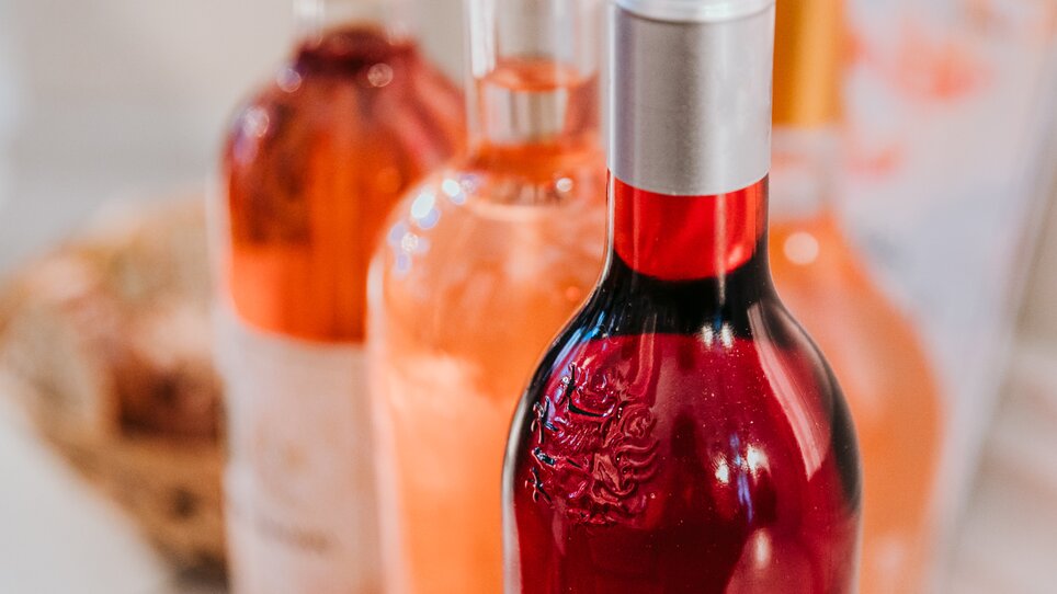 Close-up of three wine bottles with wine in different shades of rosé, from a delicate peachy pink to a strong light red. | © Johanna Lamprecht