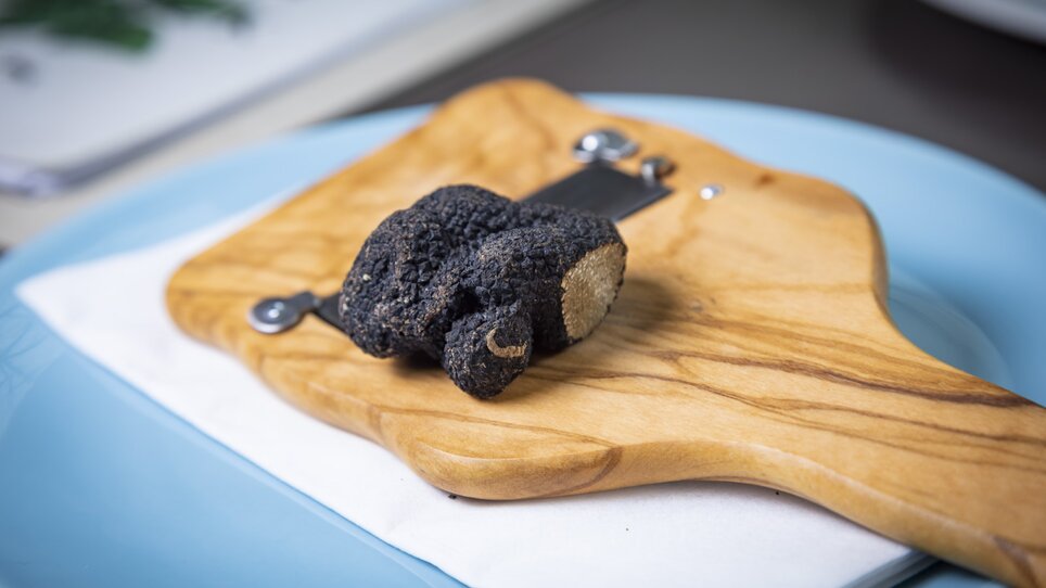 A black truffle is placed on a wooden board with a white napkin. | © Graz Tourismus_Werner Krug