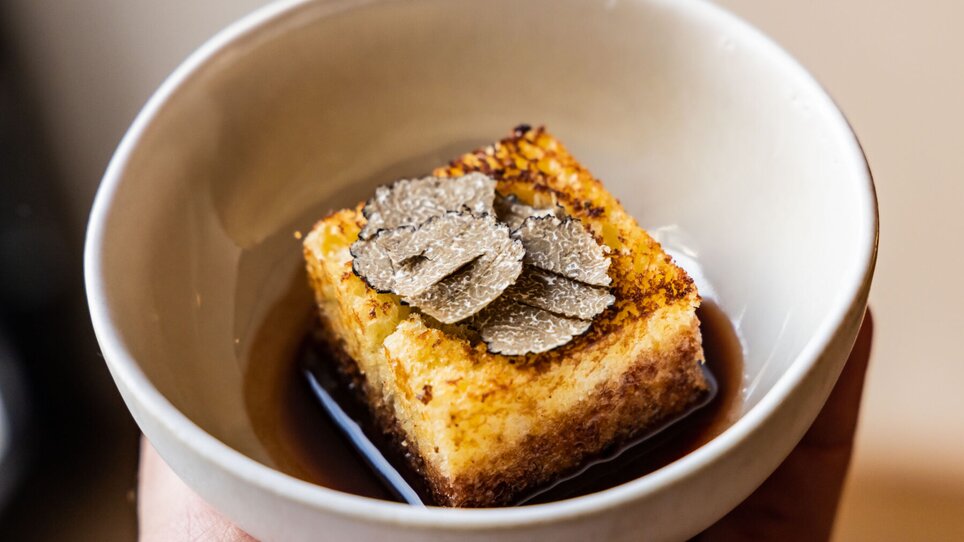 A piece of polenta topped with truffle slices in a sauce. | © Graz Tourismus - Werner Krug