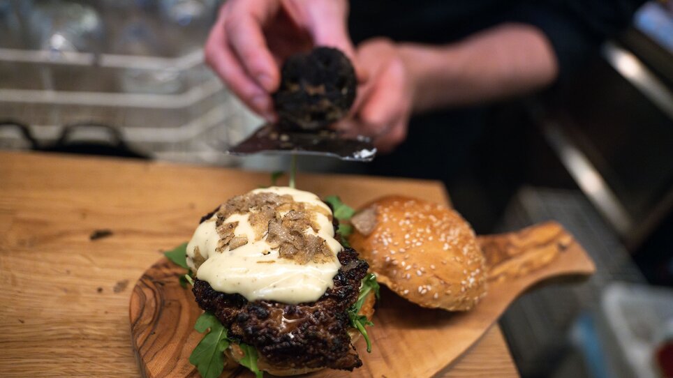 A burger with truffle slices and sauce is being prepared. | © 5komma5sinne - Rene Strasser (1) kl