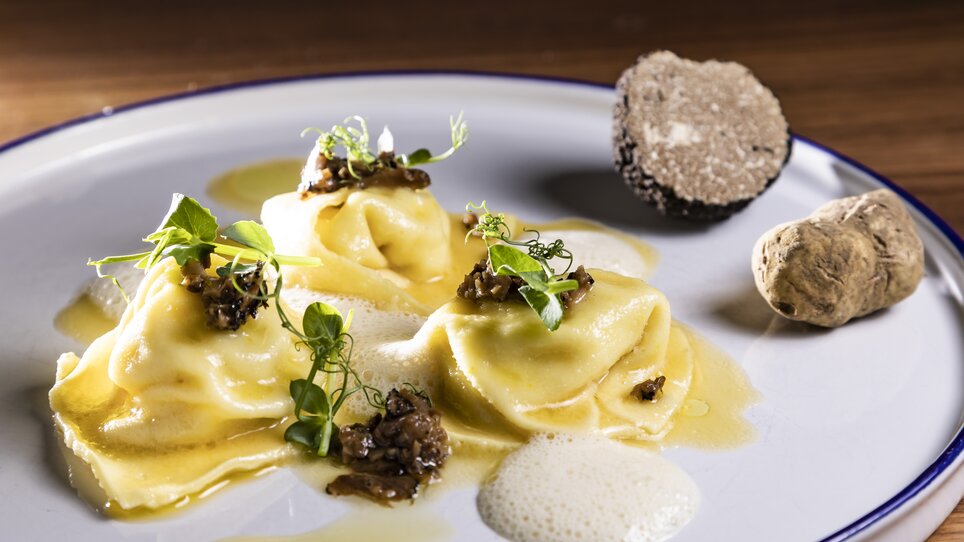 Three stuffed ravioli with truffle and sauce, garnished with herbs. | © Graz Tourismus - Werner Krug