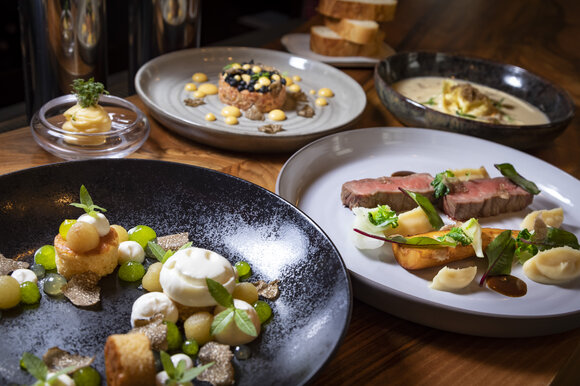 Various dishes with truffles: meat, vegetables, desserts, and sauces on plates, surrounded by bread. | © Graz Tourismus - Werner Krug