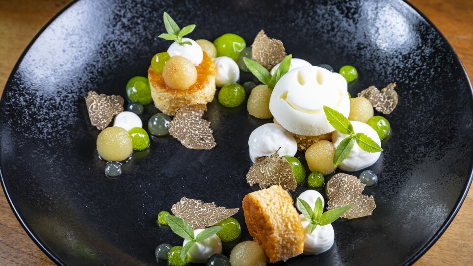 Kreatives Dessert mit Trüffel, Sorbet und Früchten auf einem schwarzen Teller. | © Graz Tourismus - Werner Krug