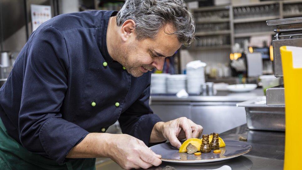 A chef artistically arranges truffle dishes on a plate in a kitchen. | © Graz Tourismus - Werner Krug