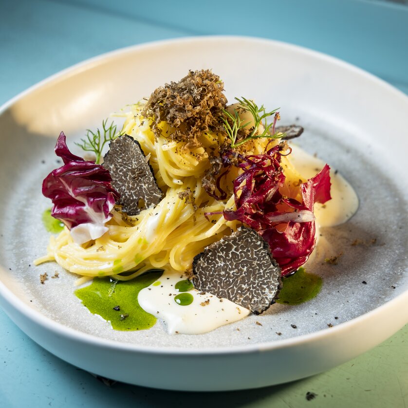 Truffle festival in Graz I Genießerei am Markt | © Graz Tourismus - Werner Krug A beautifully arranged pasta dish with truffles, radicchio, and creamy sauce on a light plate. | © Graz Tourismus - Werner Krug