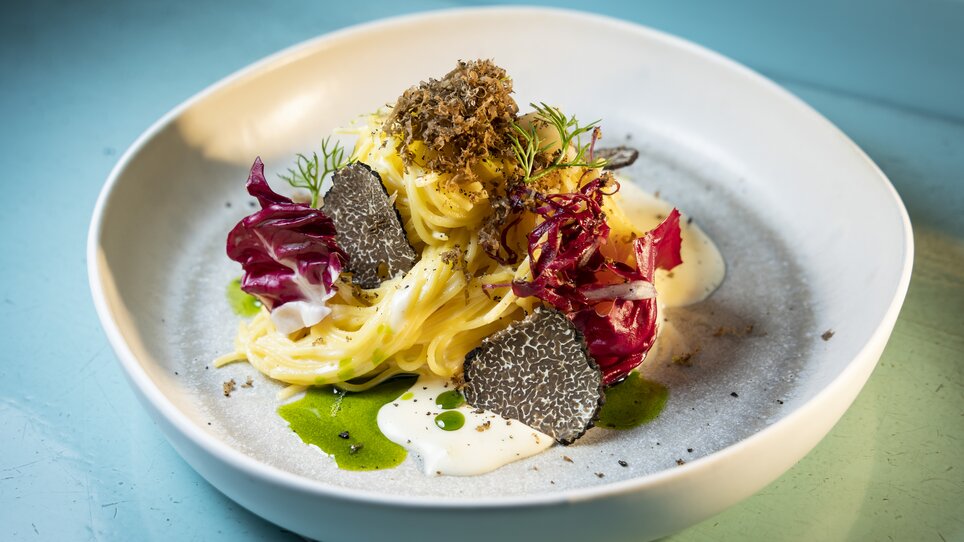 A beautifully arranged pasta dish with truffles, radicchio, and creamy sauce on a light plate. | © Graz Tourismus - Werner Krug