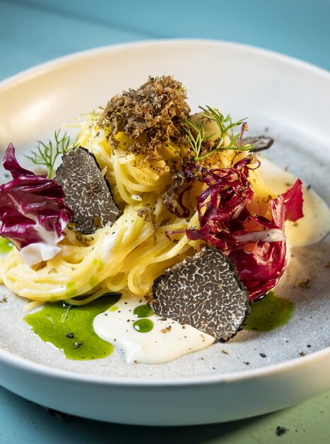 A beautifully arranged pasta dish with truffles, radicchio, and creamy sauce on a light plate. | © Graz Tourismus - Werner Krug