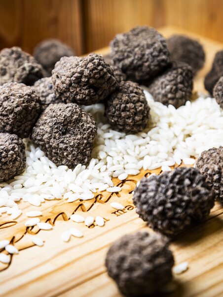 Black truffles are scattered on rice and a wooden board. | © Graz Tourismus - Werner Krug
