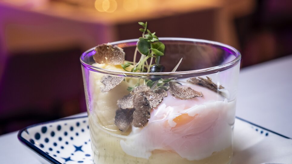 A glass with a fine dish of puree, a poached egg, and truffle slices, served on a plate. | © Graz Tourismus - Werner Krug