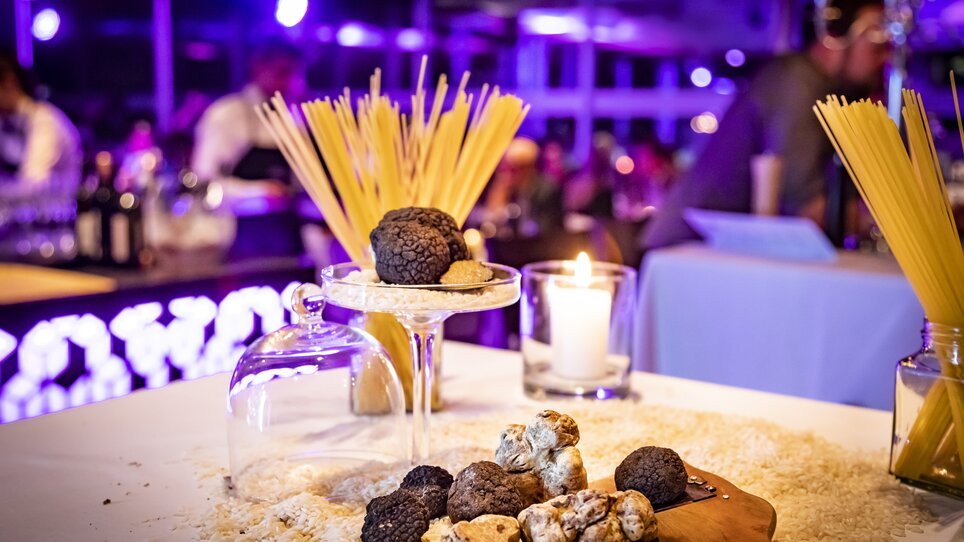 Ein Tisch mit Trüffeln, Spaghetti und einer Kerze, unter Lichtern bei einem Fest. | © Graz Tourismus - Werner Krug