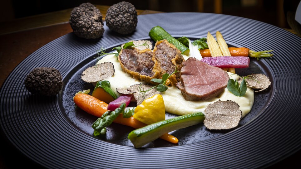Ein feines Gericht mit Fleisch, Gemüse und Trüffeln auf einem eleganten Teller. | © Graz Tourismus - Werner Krug