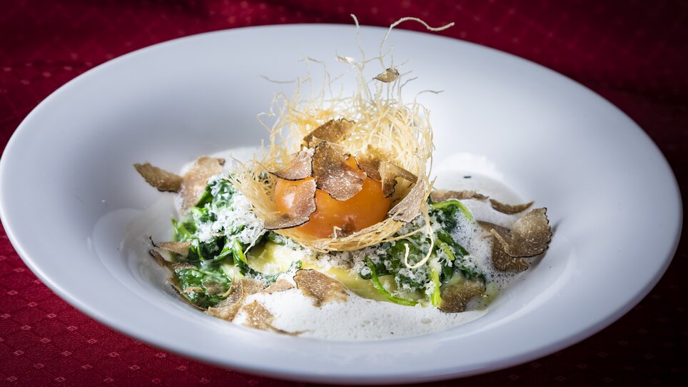Ein Gericht mit frischem Gemüse, einem Eigelb und Trüffeln, dekoriert mit frittierten Teigfäden. | © Graz Tourismus - Werner Krug