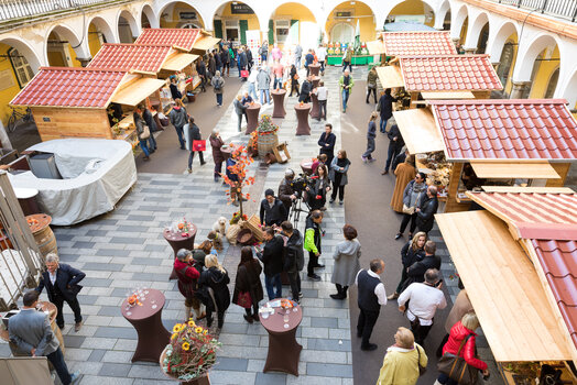 Vielbesuchter Trüffelmarkt im Paradeishof mit Verkäufern und Käufern, Holzständen und dekorativen Elementen. | © Graz Tourismus - Harry Schiffer
