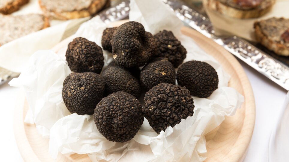 Un mucchio di tartufi neri su un piatto, circondato da carta bianca. | © Graz Tourismus - Harry Schiffer