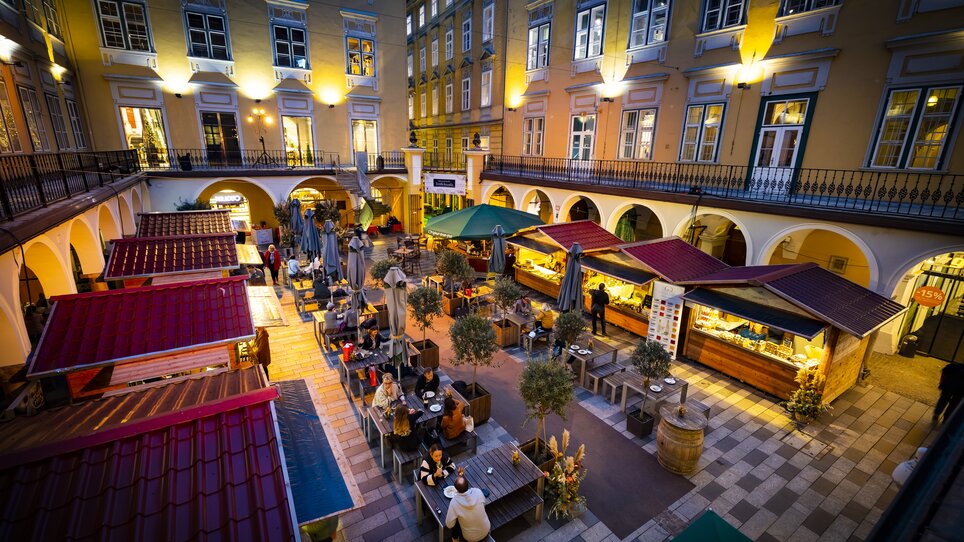 Cozy truffle market in the Paradeishof with illuminated stalls and guests. Evening ambiance with beautiful surroundings. | © Graz Tourismus - Werner Krug