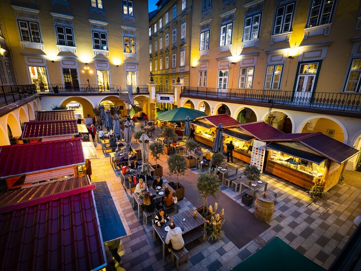 Cozy truffle market in the Paradeishof with illuminated stalls and guests. Evening ambiance with beautiful surroundings. | © Graz Tourismus - Werner Krug