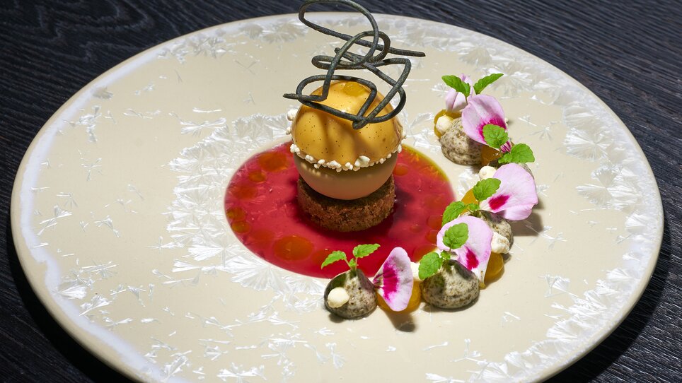 Un dessert decorato con sorbetto e fiori su un piatto. | © Bastian Knapp