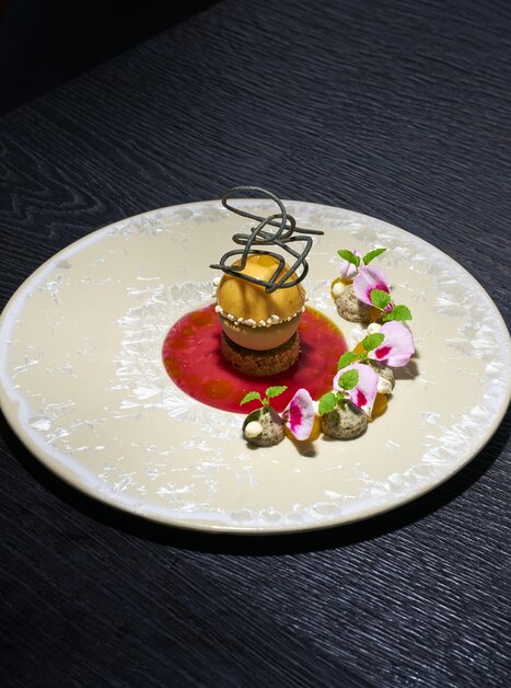 Un dessert decorato con sorbetto e fiori su un piatto. | © Bastian Knapp