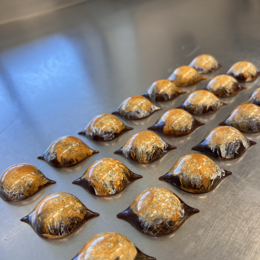 Kleine, kunstvoll geformte Pralinen auf einem Metalltisch. | © Jaimy Reisinger