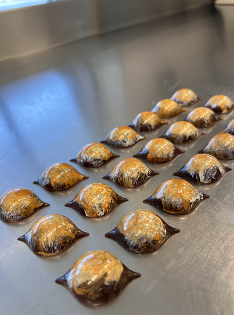 Kleine, kunstvoll geformte Pralinen auf einem Metalltisch. | © Jaimy Reisinger