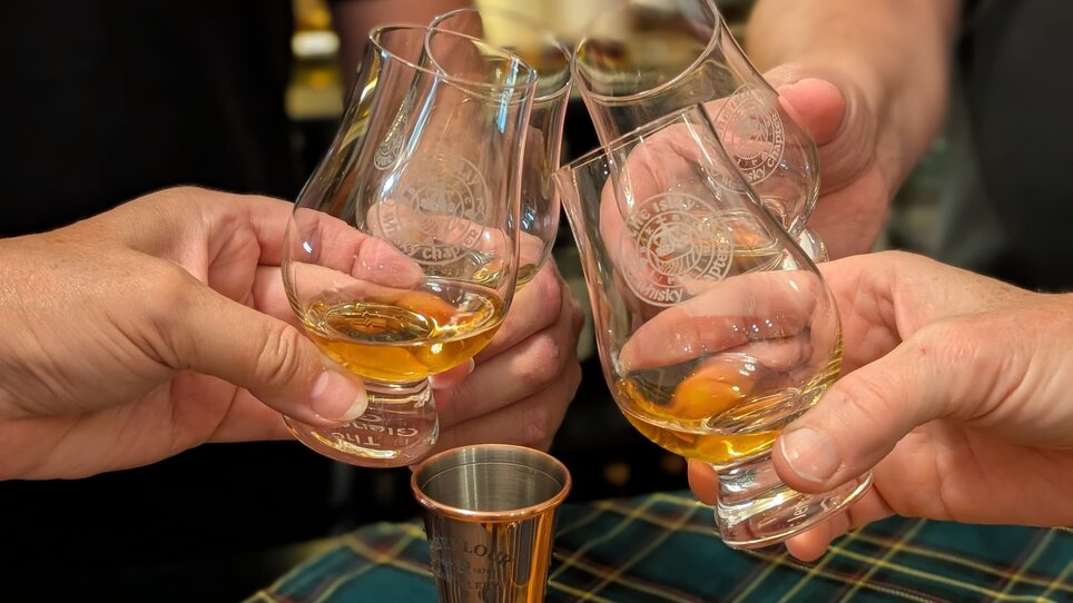 Vier Hände heben Whiskygläser zum Anstoßen. | © The Islay Whisky Chapter Austria