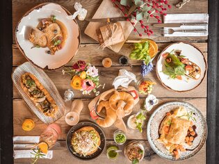 Vielfältige Gerichte, Getränke und Blumenarrangements auf einem Holztisch. | © Kunsthaus Graz