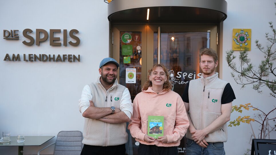 Drei Personen stehen vor "Die Speis am Lendhafen" in Graz. | © Julia Riedesser - 1000things