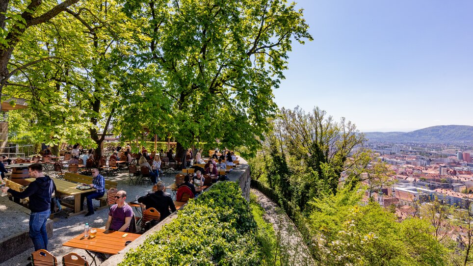 Veduta della birreria all'aperto sullo Schlossberg di Graz con una vista della città sullo sfondo. | © Werner Krug