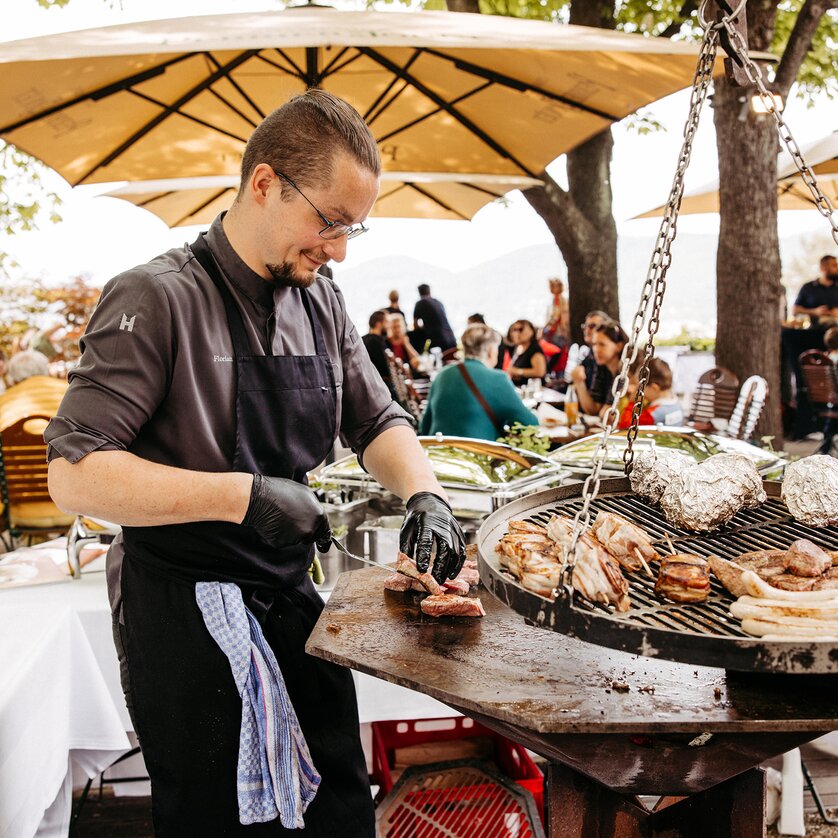 Uno chef griglia carne e verdure su una terrazza all'aperto. | © Benjamin Gasser