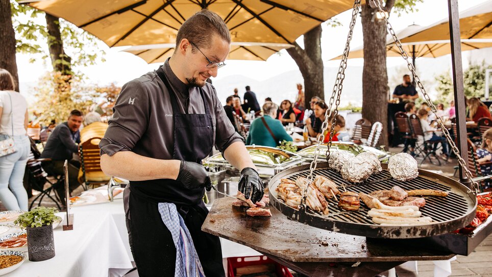 Uno chef griglia carne e verdure su una terrazza all'aperto. | © Benjamin Gasser