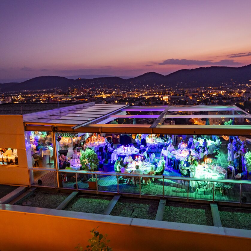 Das Restaurant SCHLOSSBERG mit Blick auf Graz bei Abenddämmerung.