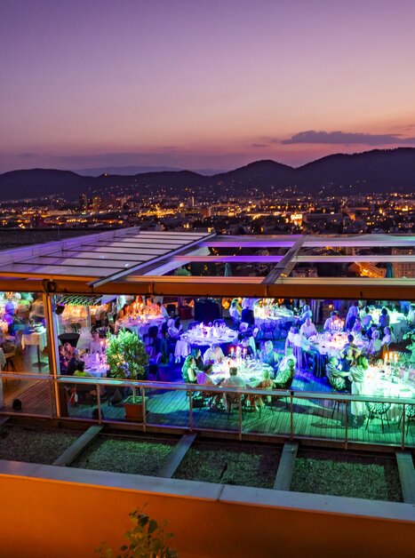 Das Restaurant SCHLOSSBERG mit Blick auf Graz bei Abenddämmerung.