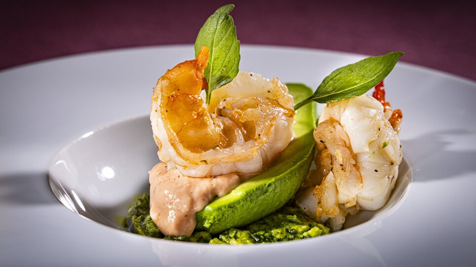 Gourmetgericht mit Garnelen, Avocado und Kräutern.