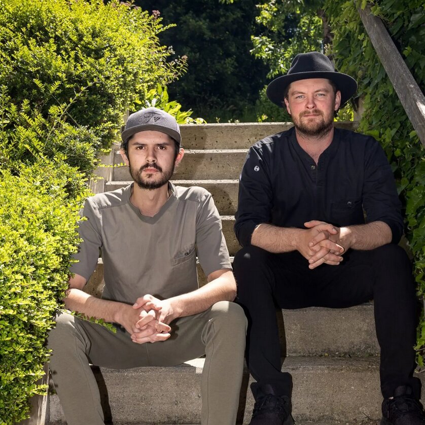 Harald Irka und Johann Schmuck sitzen auf einer Treppe, umgeben von Pflanzen. | © Kirchgasser Photography