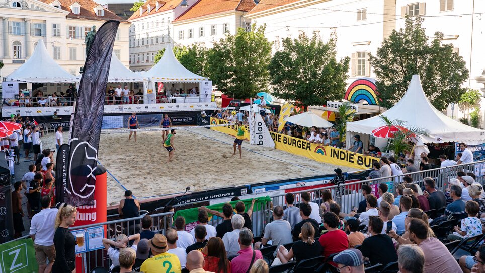 Footvolley ball match with spectators in Graz, surrounded by stands and tents. | © Mathias Kniepeiss