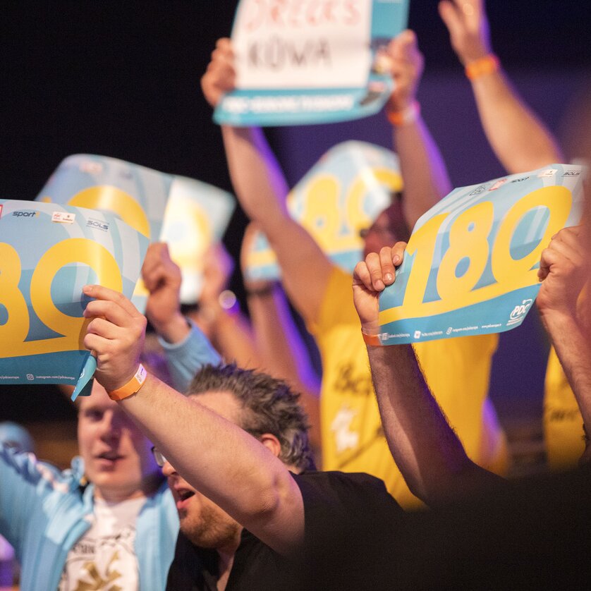Spettatori mostrano cartelli con la scritta 180 durante un torneo. | © PDC EuropeLangenbahn von Moltke GmbH