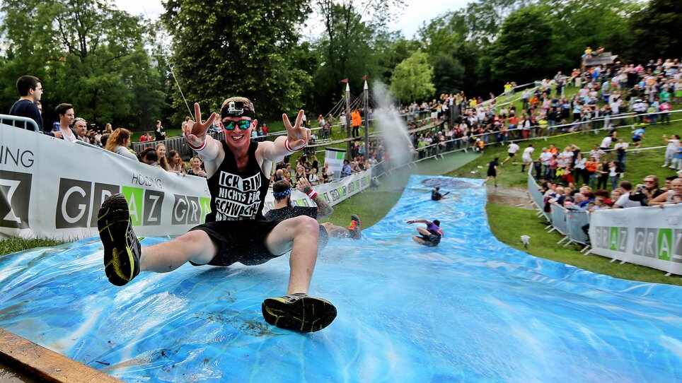 Ein Teilnehmer beim GRAWE-Grazathlon rutscht die Wasserbahn hinunter. | © GEPA picturesCompanyCode