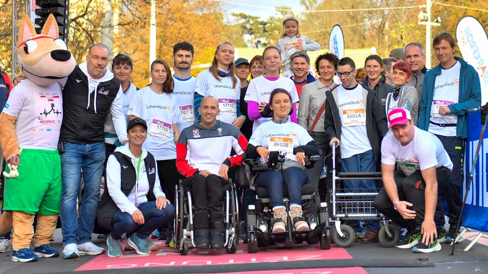 Group of people in running shirts, some sitting in wheelchairs, before the start of the Graz Marathon. | © GEPA